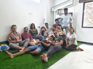 蓬蒂切里Eness Hostels Pondicherry的一群人坐在一间房间里,坐在草地上