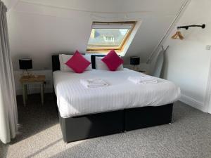 纽马基特Kings Lodge的一间卧室配有带粉红色枕头的床和窗户。