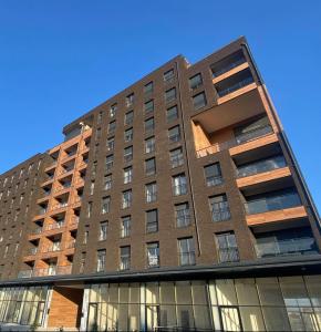 普里什蒂纳DAF apartaments的一座高大的砖砌建筑,设有窗户,天空蔚蓝
