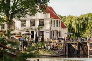 阿姆斯特丹The Quay Amsterdam - FREE PARKING的一座建筑物,人们坐在河边