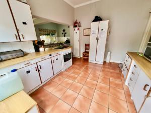 谢普斯敦港23 Ambleside Holiday Retreat by the sea的厨房配有白色橱柜和瓷砖地板。