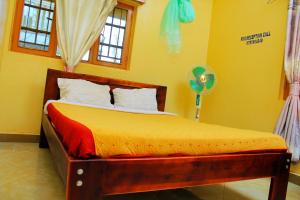金贾Kenthill Guest House的一间卧室设有一张黄色墙壁和窗户的床