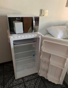 布卢梅瑙Suíte Aconchego的空冰箱,门打开在房间里