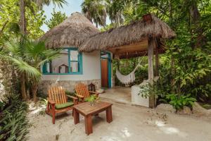 图卢姆Dos Ceibas Tulum Feel Good Hotel的房屋设有两把椅子、一张桌子和吊床