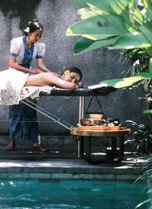 乌布Madara Ubud Villas的女人躺在游泳池旁边的床上
