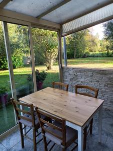 Entre Puy-de-Dôme et Corrèze Appartement pour 4 personnes avec terrasse et jardin的门廊上放有纱窗的木桌和椅子
