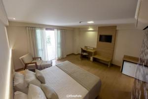 佩德拉阿祖尔Vista Azul Hotel的酒店客房配有一张床、一张书桌和一台电视。