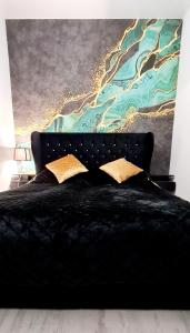 博茨科沃Apartamenty Aquarius Gold Boszkowo的卧室配有一张黑色床,墙上挂有绘画作品