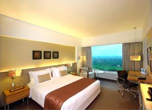 艾哈迈达巴德Fortune Select SG Highway, Ahmedabad - Member ITC's Hotel Group的配有一张床、一张书桌和一扇窗户的酒店客房