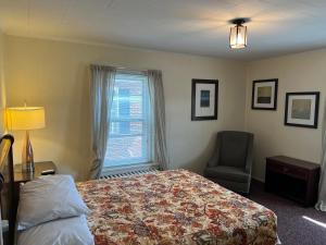 赫尔希西蒙斯套房汽车旅馆的卧室配有床、椅子和窗户。