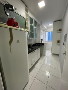 大普拉亚Ap aconchegante 12 min a pé p Praia的白色的厨房配有冰箱和水槽