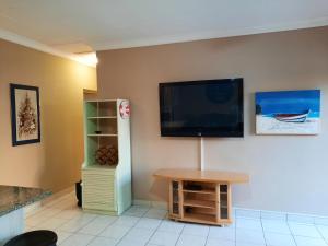 乌旺戈海滩Uvongo square Unit 24的客厅的墙上配有平面电视。