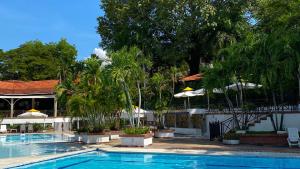 吉拉尔多特On Vacation Girardot Resort的度假村内带树木和遮阳伞的游泳池