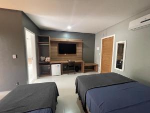 圣阿马鲁Chalé Murici Lençóis的一间卧室配有两张床、一张桌子和一台电视。