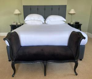 莱姆里吉斯弗赫里酒店的一张大床,配有黑色皮革床头板和白色枕头