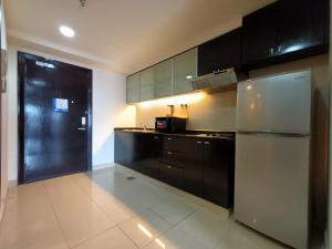 Kampong PenagaResort Suites by Landmark at Bandar Sunway Sunway Lagoon的厨房配有黑色橱柜和不锈钢冰箱