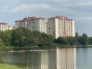 万挠Homestay Ar Rayyan RESIDENSI LAGUNA BIRU的一群人划船在河上,有高大的建筑