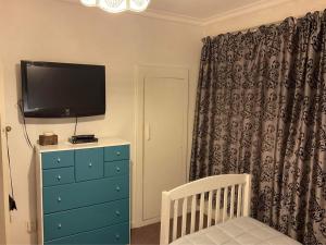 因弗卡吉尔Bungalow on Centre的一间卧室配有电视和带婴儿床的梳妆台。