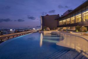 曼谷Asawin Grand Convention Hotel的一座游泳池,在晚上在一座建筑的顶部
