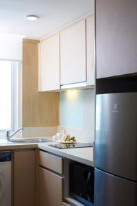 曼谷曼谷碧武里47莎玛服務式公寓的厨房配有白色橱柜和不锈钢冰箱