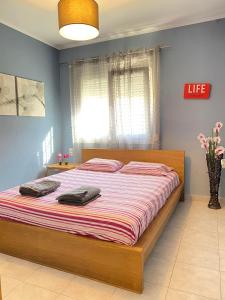 卡瓦拉KOLOKOTRONIS’ HOUSE的一间卧室配有一张带条纹床单的大床和窗户。
