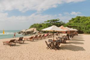 埃尔扎伊诺Ecohabs Tequendama Playa Cañaveral Parque Tayrona的沙滩上摆放着桌椅和遮阳伞