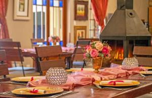 博克斯堡非洲精品酒店​​O.坦博的一张桌子,上面放有盘子和花瓶,还有一个壁炉
