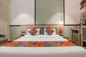 新德里FabHotel Heaven In的一间卧室配有一张大床和五颜六色的被子