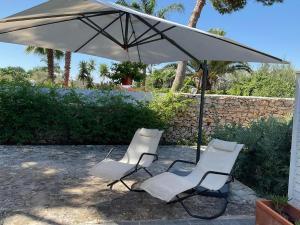 泰拉西尼la Casetta di Laura的庭院里设有两把白色椅子和一把遮阳伞