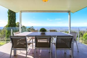 Eagle HeightsBeautiful Home with Breath-taking Views Mt Tamborine的房屋阳台上的餐桌和椅子