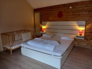 Bertognele sanglier的一间卧室配有一张带两盏灯和一张婴儿床的床。