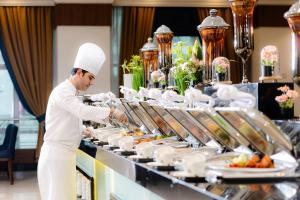 麦地那MADEN Hotel的厨师在自助餐线上准备食物