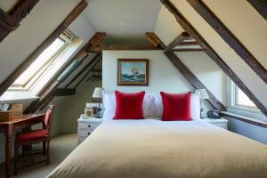 南安普敦猪在墙上酒店的一间卧室配有一张带红色枕头的床和一张书桌