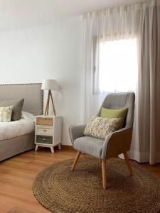 巴尔韦尔德Apartamentos Los Catorce, EL Hierro的一间卧室配有椅子、床和窗户