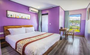西哈努克Junlan Hotel的一间卧室设有紫色的墙壁和一张带书桌的床