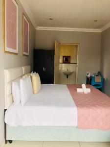 乌姆塔塔Innoview Lodge的卧室配有一张白色大床和粉色毯子