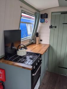 Mini Escape - 2 Berth Narrowboat on the Grand Union, Hertfordshire的厨房配有炉灶和茶壶