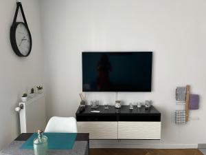 德朗西Superbe studio lumineux haut de gamme tout confort的一间客厅,在白色的墙上配有电视