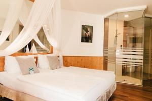 滨湖新锡德尔达斯斯塔德豪斯酒店的卧室配有白色的床和玻璃淋浴间