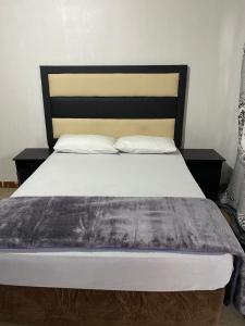 索韦托Soweto Towers Guest Accommodation的一间卧室配有一张带黑色床头板和白色枕头的床。
