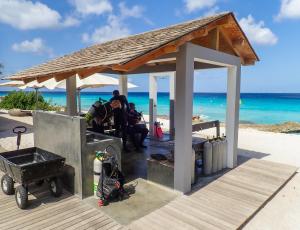 克拉伦代克Delfins Beach Resort的一群人坐在海滩上的一个凉亭下