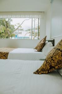 帕斯托Hotel Parque Reservado的白色客房的两张床,设有窗户