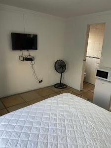 索韦托Soweto Towers Guest Accommodation的卧室配有白色的床和墙上的电视。