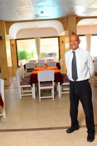卢克索Shady Hotel Luxor的站在饭厅前的领带上的人