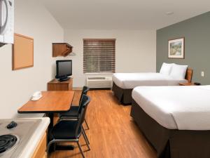 Portage LakesExtended Stay America Select Suites - Akron - South的酒店客房设有两张床、一张书桌和一个厨房。