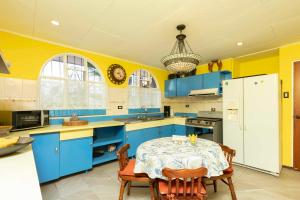 圣何塞XIN Bed&Breakfast的蓝色和黄色的厨房,配有桌子和冰箱