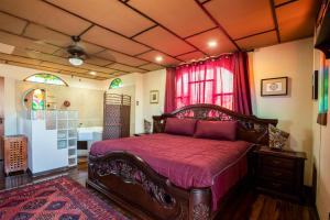 圣何塞XIN Bed&Breakfast的一间卧室配有一张带红色床罩的木床