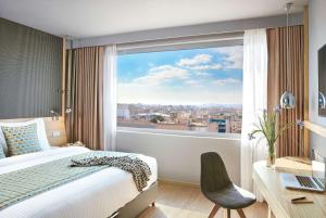 雅典大雅典温德姆酒店的一间卧室配有一张床、一张书桌和一个窗户。