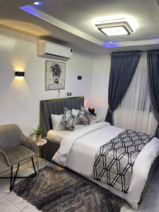 阿布贾Morak Homes - Luxury 4 bed home with PS5, 24hrs electricity, Super fast Wifi, Snooker, Games room - in a secured estate的一间卧室配有一张床和一把椅子