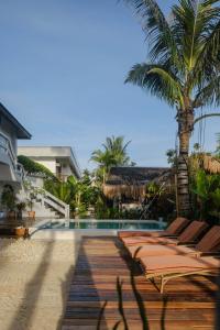 卢纳将军城Happiness Beach Resort Siargao的游泳池旁的一排躺椅和一棵棕榈树